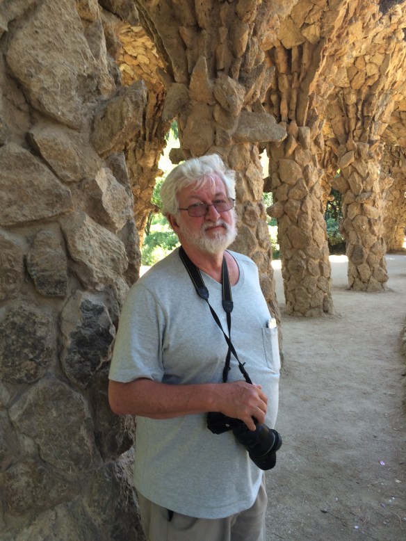 Tom standing under a Gaudi-designed bridge in Parc Guel